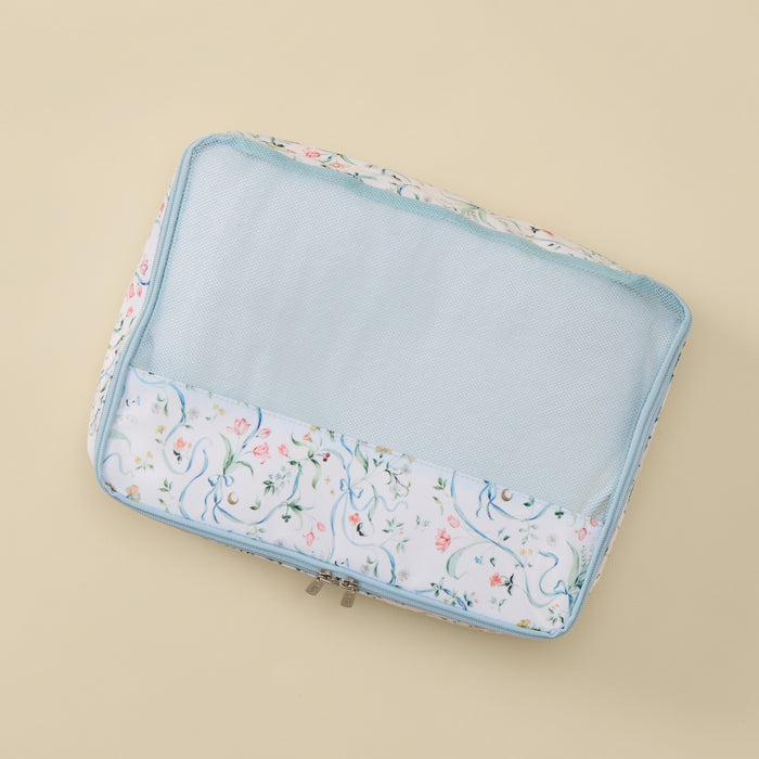 A rectangular mesh zippered travel organizer pouch with a white floral print border and a light blue interior, shown on a solid beige background.