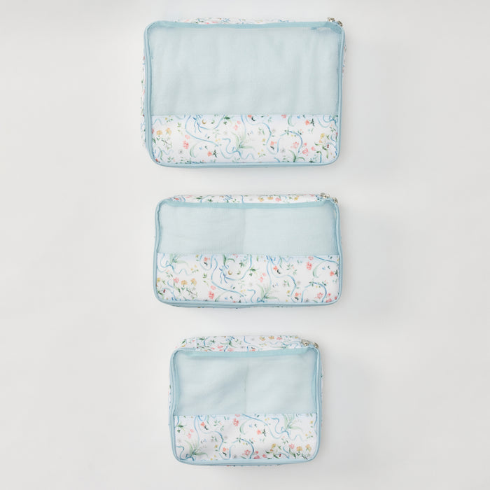Three matching zippered fabric pouches arranged vertically on a light gray background. Each pouch has a light blue mesh upper section and a white lower section with a delicate pastel floral print.
