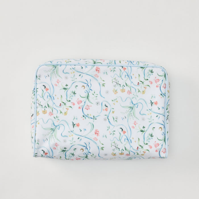 A rectangular toiletry bag featuring a delicate pattern of blue ribbons, green vines, and small pink and yellow flowers, accented by light blue piping, set against a plain light gray background.