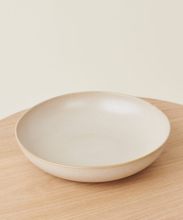 The Pacific Serving Bowl is a simple, shallow off-white ceramic bowl with a slightly raised rim—an elegant addition to your dinnerware collection.