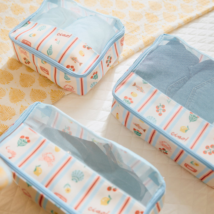 Set of Weezie's patterned travel packing cubes in Dolce Vita variant, arranged on a bedspread