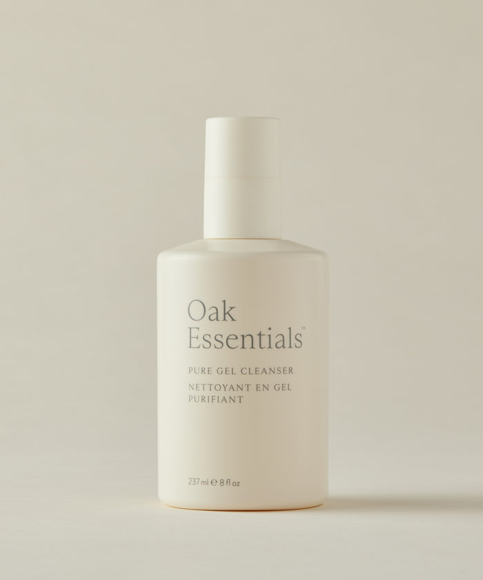 A white bottle of Pure Gel Cleanser with a pump, minimalist gray text on the front, set against a neutral beige background—your go-to gel cleanser for a clarifying clean and brighter complexion.