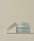 A light blue Refining Mask sits in an open glass jar labeled “Refining Mask” on a neutral background, with the lid resting at an angle beside it.