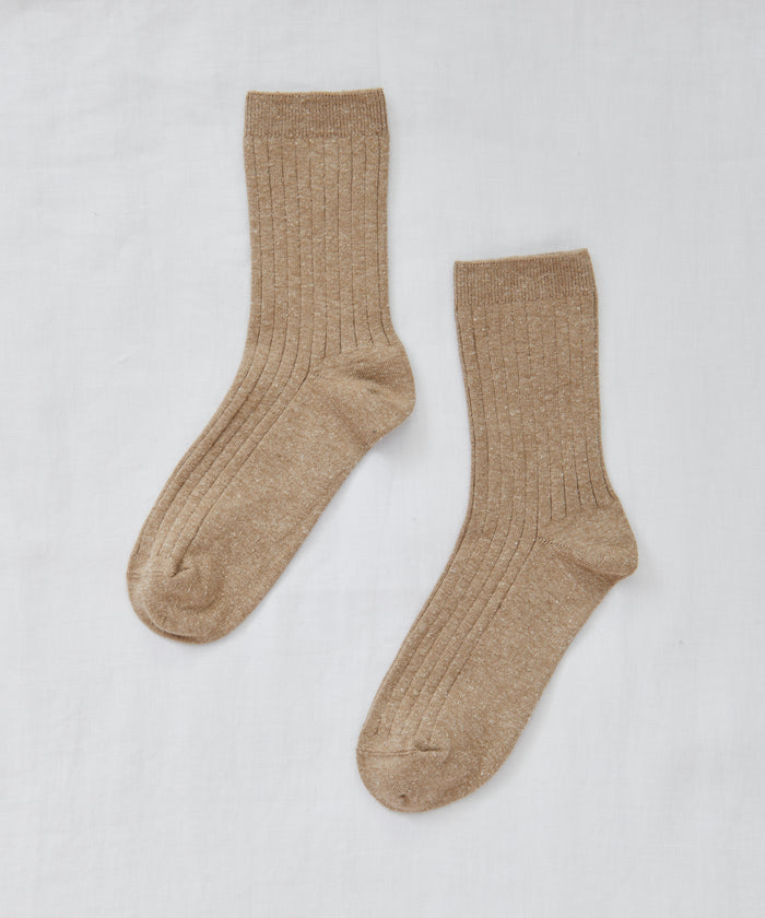 A pair of Rib Socks in light brown, designed for all-season comfort with a lightweight feel, are laid flat on a white fabric background.