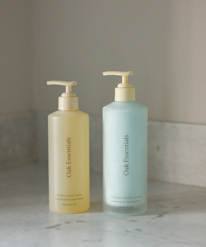 The Silk Body Duo by Oak Essentials, featuring the yellow Awaken Body Wash and pale blue Luminous Body Lotion, sits on a marble surface, delivering skin-soothing hydration for your daily routine.
