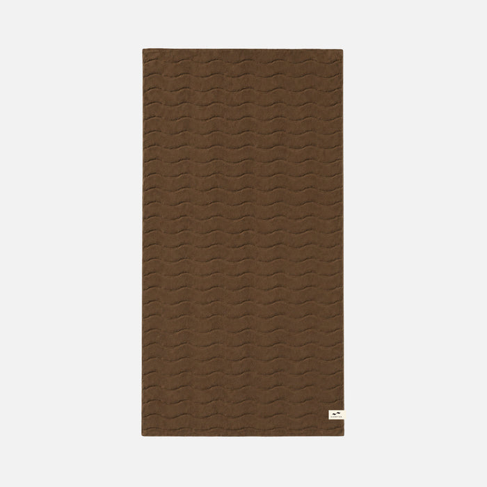 Brown bath towel with wavy sculpted texture and small white corner label.
