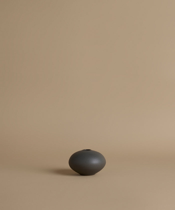Black ceramic vase on a beige background