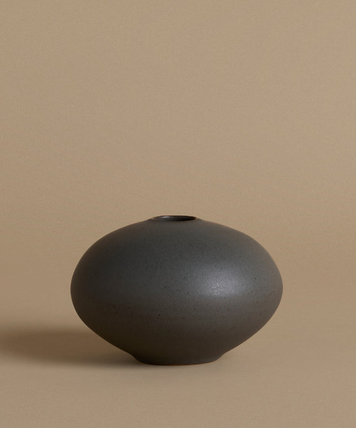 Black ceramic vase on a beige background