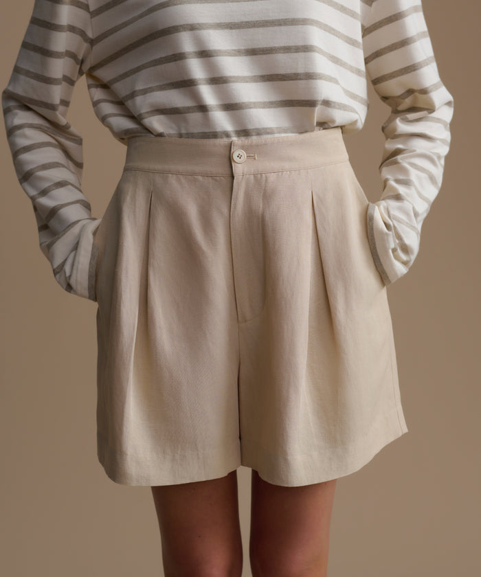 Person wearing beige shorts and a striped long-sleeve shirt against a plain background