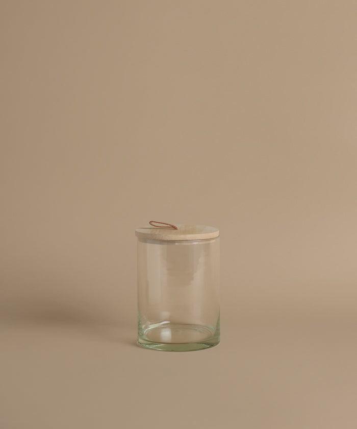 A glass canister against a beige background.