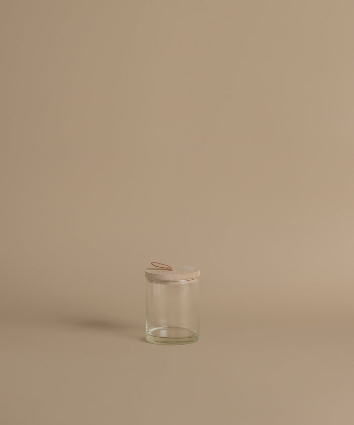 A glass canister against a beige background.