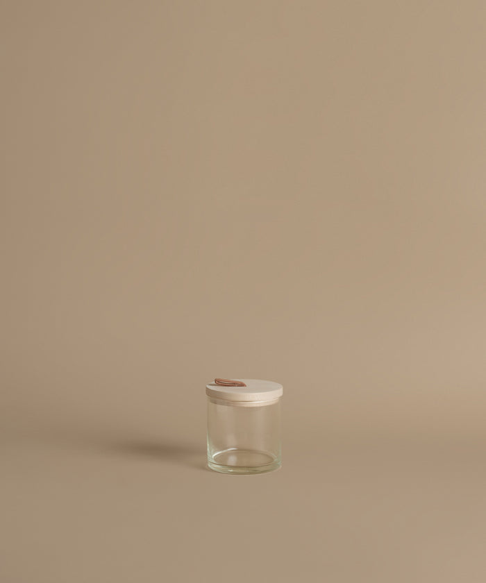 A glass canister against a beige background.