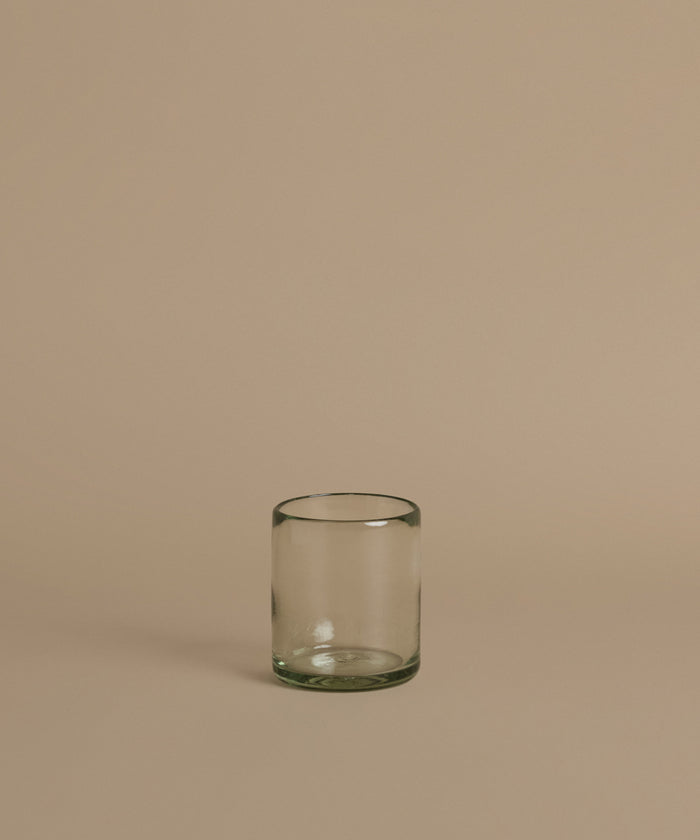 Recycled glass cup against a beige background.
