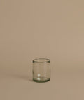 Recycled glass cup against a beige background.
