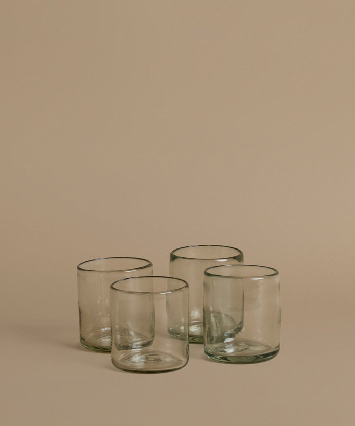Recycled glass cups against a beige background.