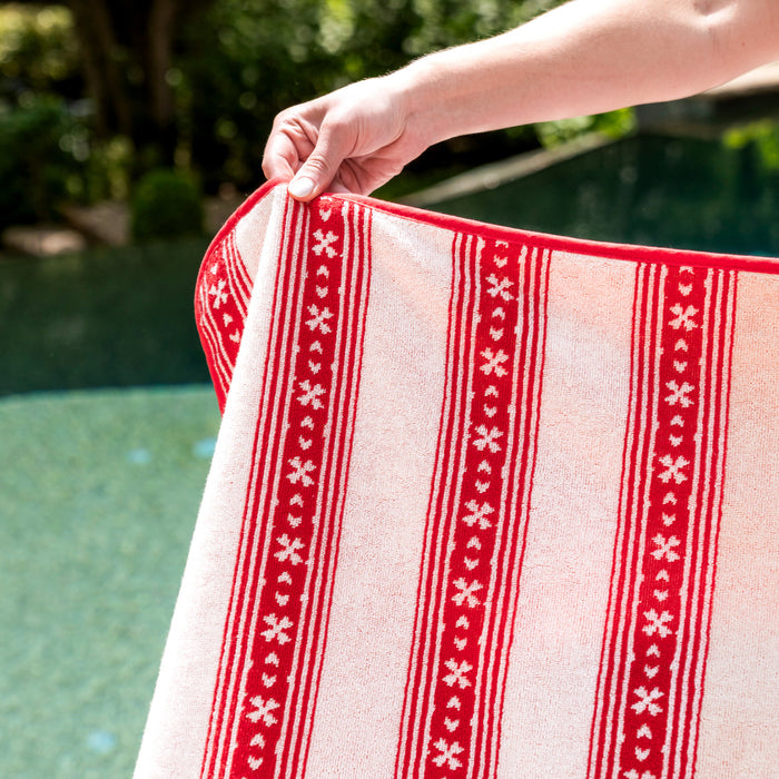 Red and white patterned towel held by a person with a pool in the background