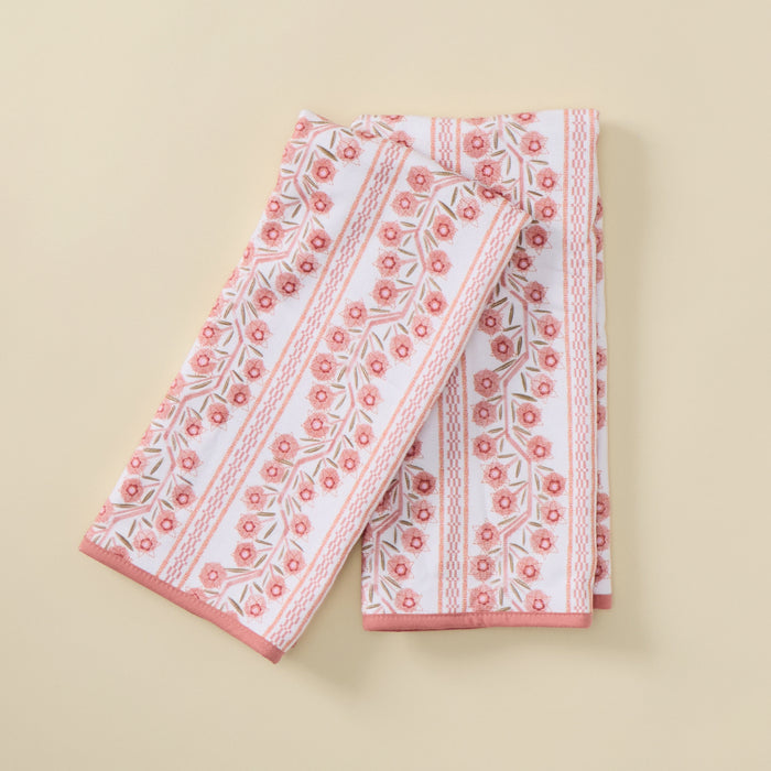 Two folded kitchen towels featuring a pink and peach floral climbing vine pattern with a solid pink border.