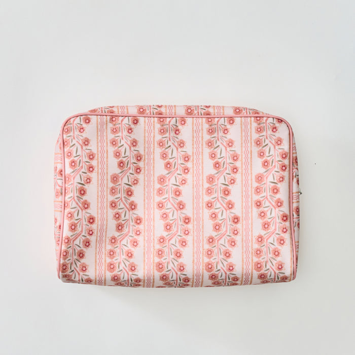 A rectangular toiletry bag featuring a pink and coral floral climbing vine stripe pattern with light pink piping, shown flat against a plain light background.