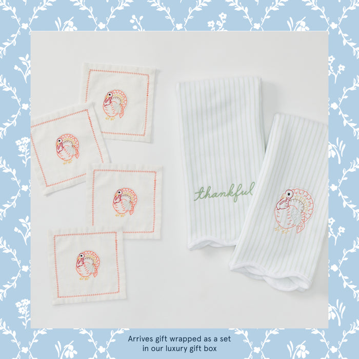 Two green striped kitchen towel and four square cocktail napkins, with embroidered turkey designs, a text at the bottom says "Arrives gift wrapped as a set in our luxury gift box".