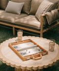 Backgammon set on a round table with a couch in the background