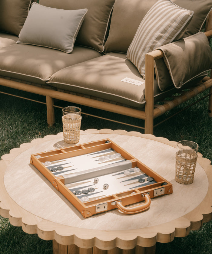 Backgammon set on a round table with a couch in the background
