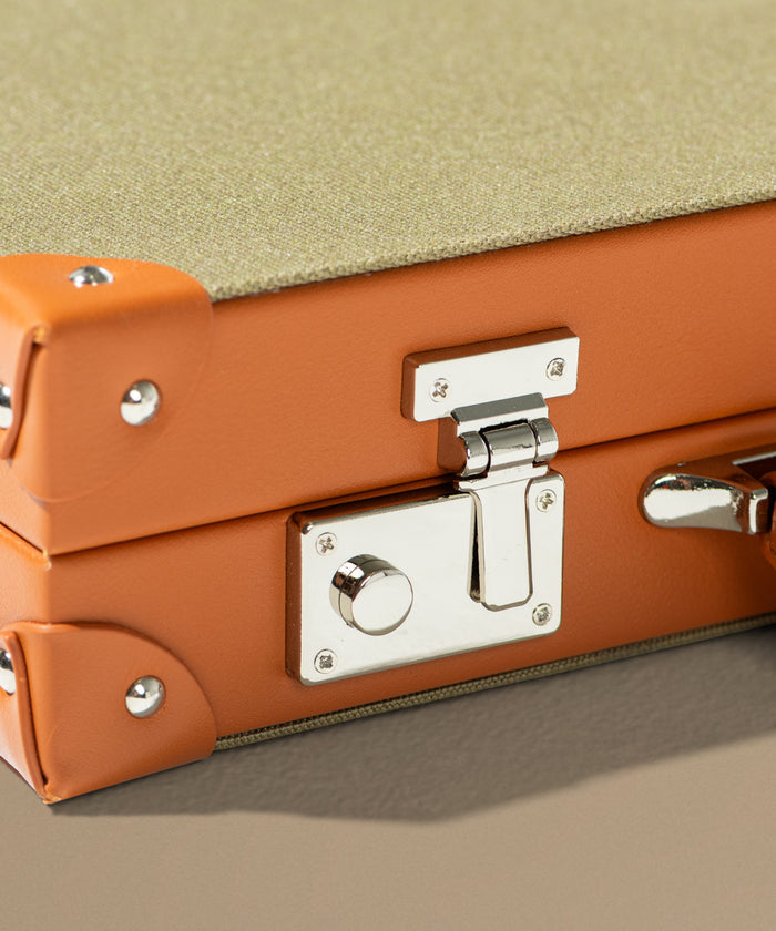 Close-up of an orange backgammon set with a silver lock on a beige background