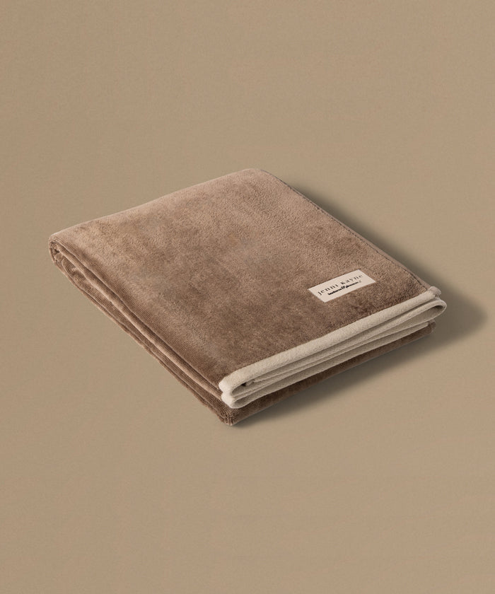 Brown towel with a brand label on a beige background