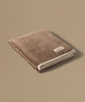 Brown towel with a brand label on a beige background