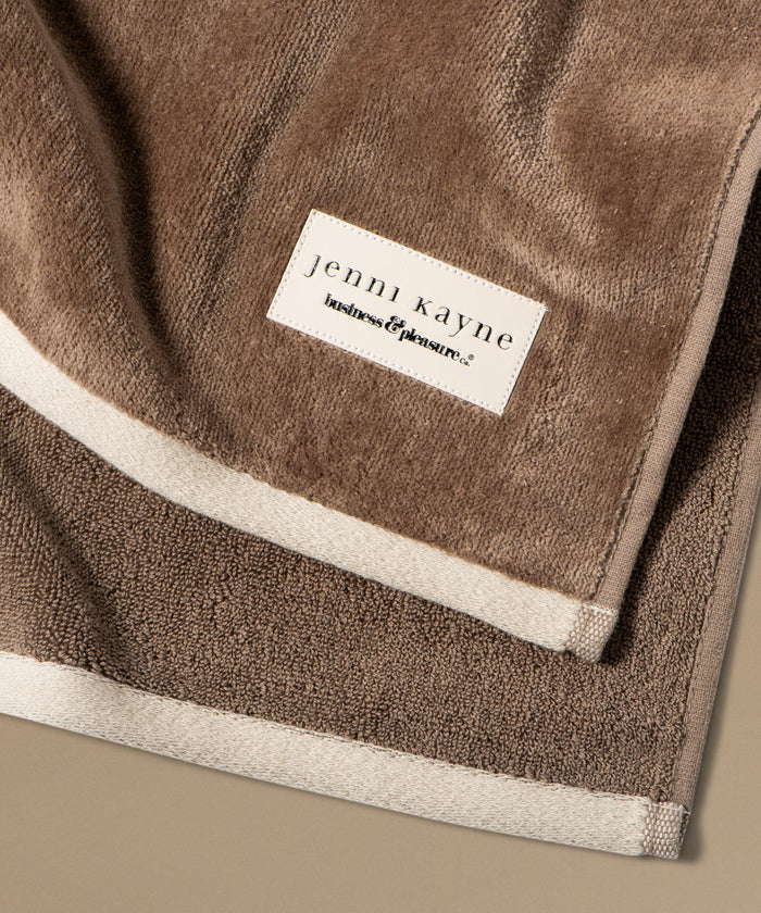 Brown towel with 'jenni kayne' label on a beige background