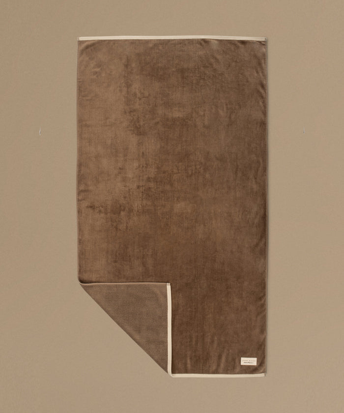 Brown towel with 'jenni kayne' label on a beige background