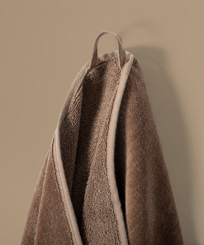 Brown towel hanging against a beige wall