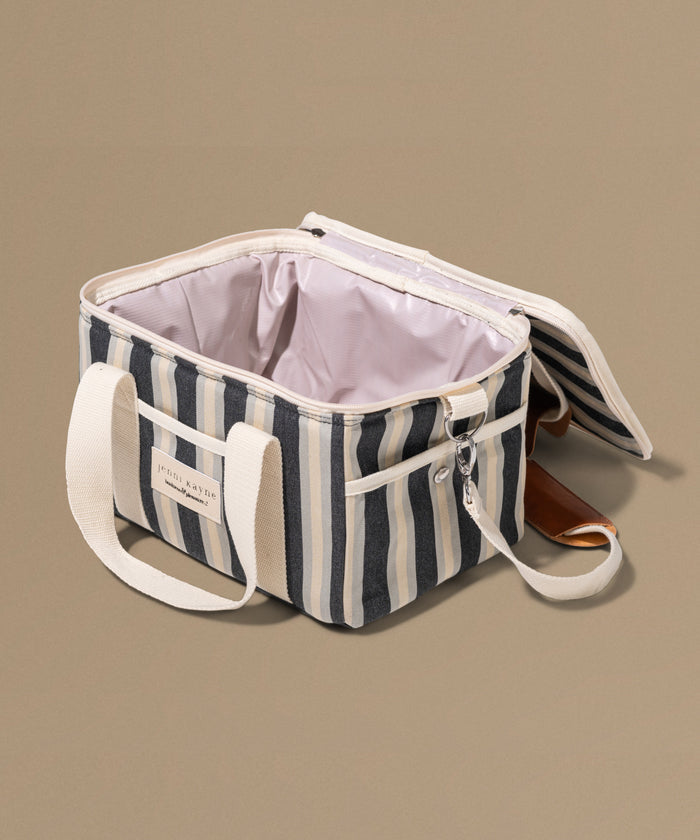 Striped cooler bag with white handles on a beige background