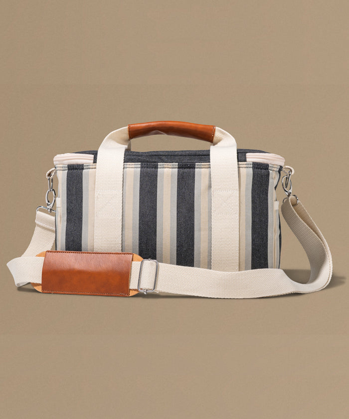 Striped bag with brown leather accents on a beige background