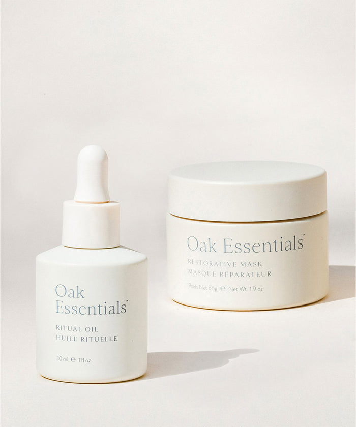 The Reset Duo—featuring two white Oak Essentials containers, a Ritual Oil dropper bottle and a Restorative Mask jar—is displayed against a soft, neutral background, making it an ideal choice for any elevated skincare routine.