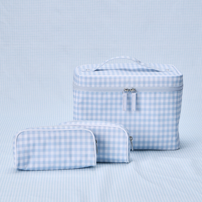 A Weezie Travel Bundle in Light Blue Gingham, consisting of one large, structured vanity case with a top handle and two small toiletry bags, all featuring a matching blue and white checkered pattern.