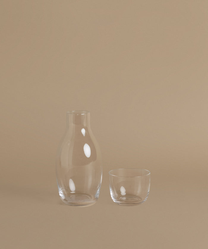 A glass carafe against a beige background.