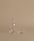 A glass carafe against a beige background.