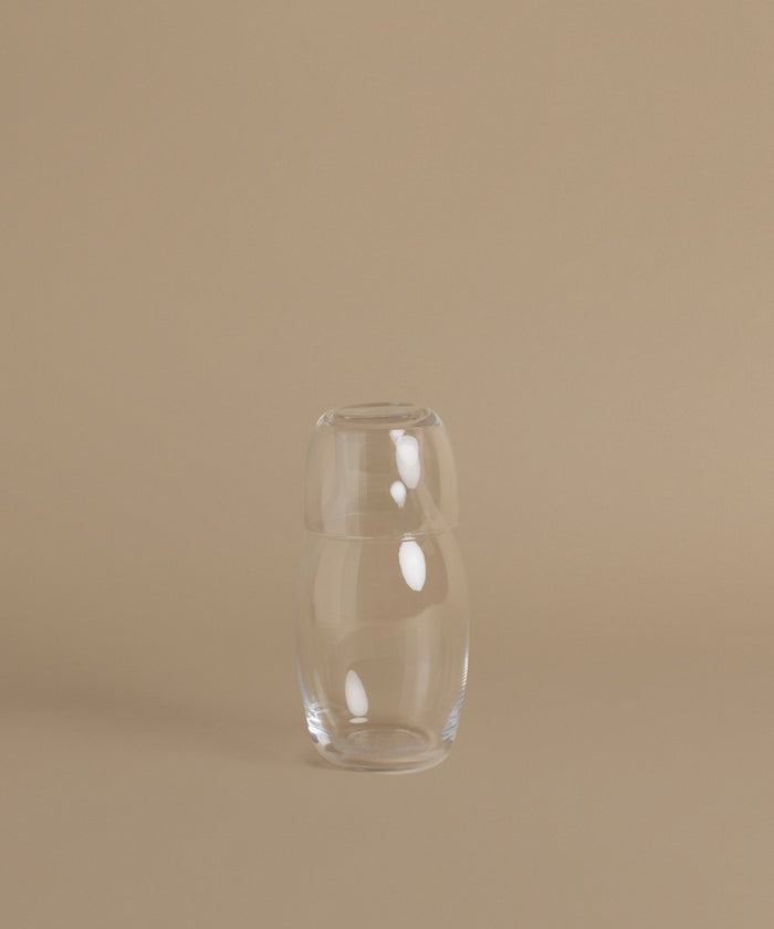 A glass carafe against a beige background.