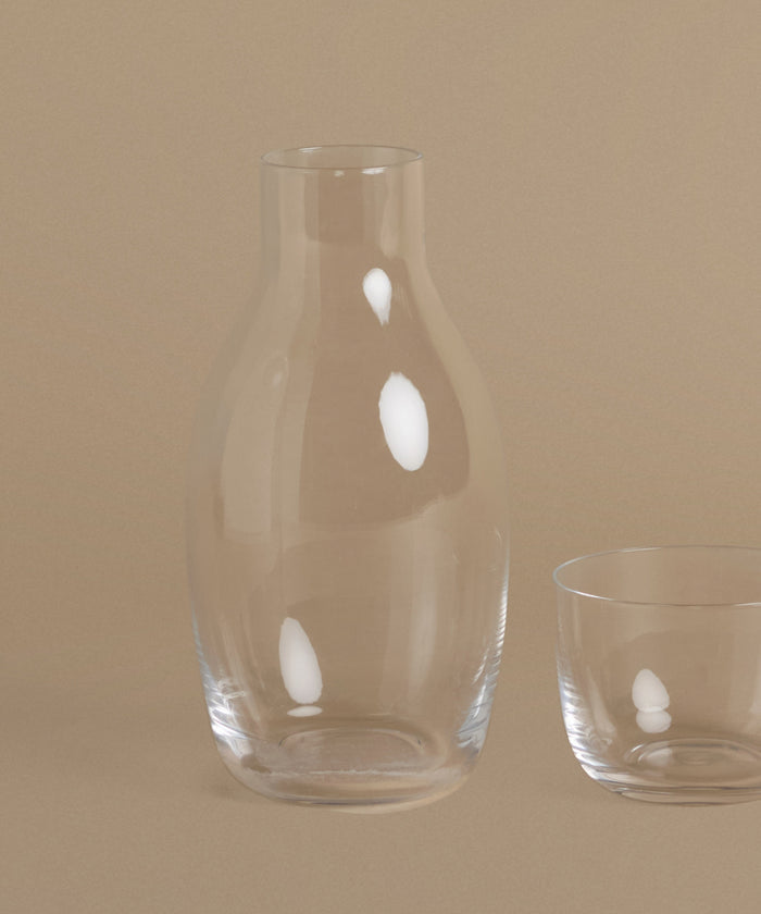 A glass carafe against a beige background.