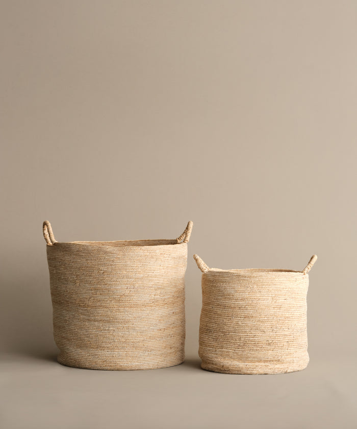 Two Woven Storage Baskets with handles, one large and one small, are placed side by side against a taupe background—an elegant storage solution for any home.